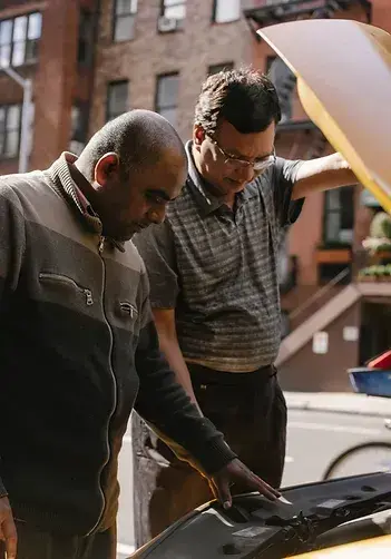 Two men inspecting vehicle damage after an accident